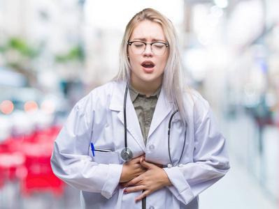 年轻的金发医生女人过孤立的背景,手在肚子上,因为消化不良,痛苦的