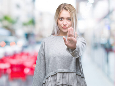 年轻的金发女人在孤立的背景下做停止用手掌唱歌。 警告表情，脸上有负面和严肃的手势。