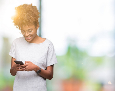 年轻的非裔美国妇女使用智能手机，在孤立的背景下，快乐的脸站着，微笑着，露出自信的微笑，露出牙齿