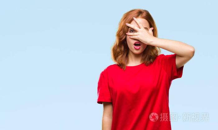 孤立的背景上偷看,震惊地覆盖着脸和眼睛,用手透过手指看着尴尬的表情