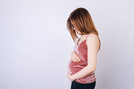 年轻孕妇双手捂住肚子的照片