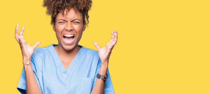 年轻的非裔美国医生女人在孤立的背景下庆祝疯狂和疯狂的成功，举起手臂和闭上眼睛尖叫兴奋。 赢家概念