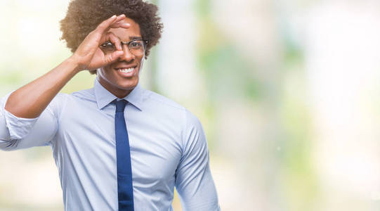非洲裔美国商人戴着眼镜，在孤立的背景下做着好的手势，用手微笑，用快乐的脸透过手指看。