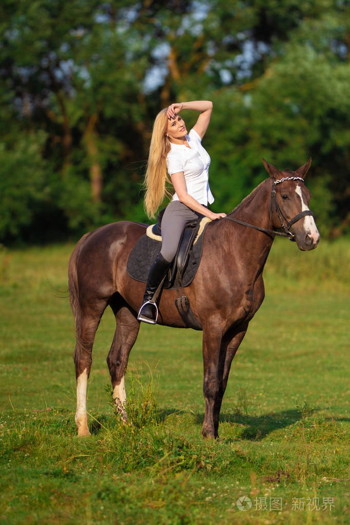 一个金发的年轻女子,一个牛仔在牧场上训练一匹马
