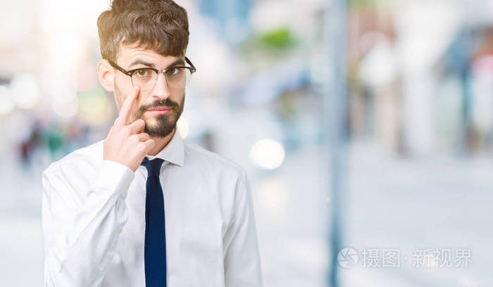 年轻英俊的商人戴着眼镜背景偏僻眼睛盯着你看着你摆出可疑的表情