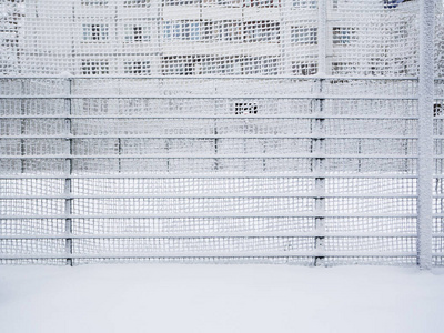 篱笆上覆盖着雪。 雪覆盖的格子。