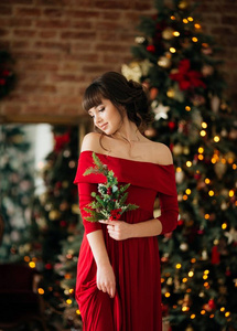 一位身穿红裙在圣诞树旁摆姿势的美女