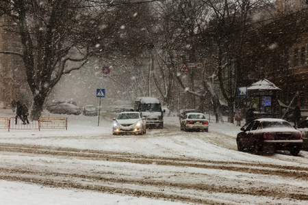 冬天城市街道上的大雪。 汽车上覆盖着雪滑的道路。 冬天的坏天气大雪和暴风雪。 行人在大雪下行走。 冬天和暴风雪