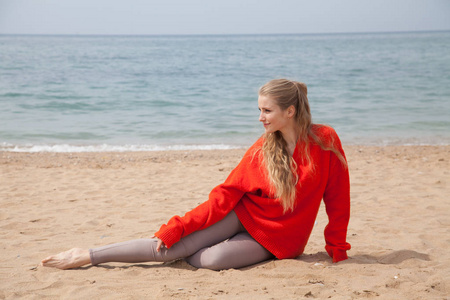 一个女人坐在一个荒芜的沙滩上, 望着大海