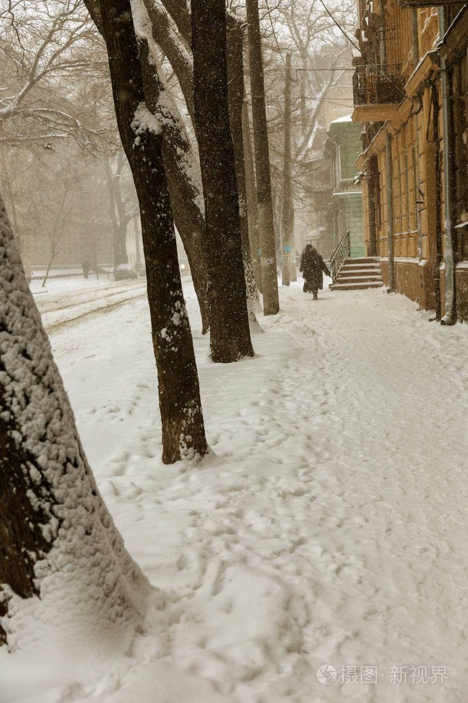 冬天城市街道上大雪纷飞.汽车上覆盖着雪,路滑.