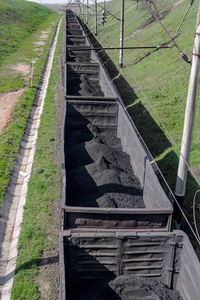 用铁路运输的黑色细煤的货运铁路汽车。 上面的风景。 小动作模糊。