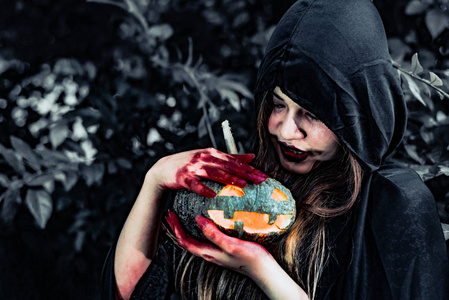 恶魔女巫在神秘森林里照顾南瓜. 鬼和恐怖的概念. 万圣节主题.