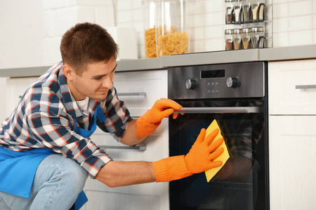 男人用抹布打扫厨房烤箱