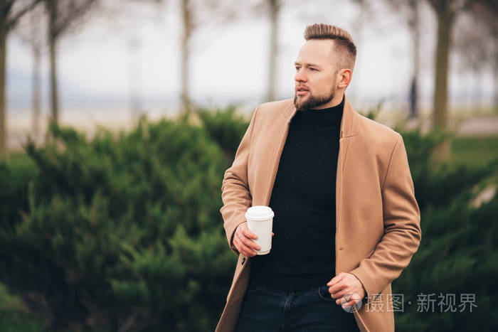 在公园里喝咖啡的帅气的胡须年轻人, 在杯子上复制空间