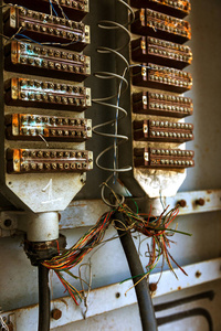 城市街道的旧模拟电话总机。 破碎的被掠夺的废弃的旧电话总机有线固定线路。 电缆管道吊挂柜内电话线
