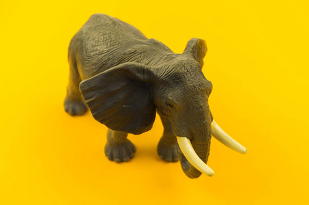 黄色背景上的大型塑料大象玩具。 儿童用的非洲动物。 复制空间。