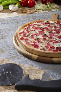 在灰色桌面上贴上火腿和蘑菇的意大利披萨。