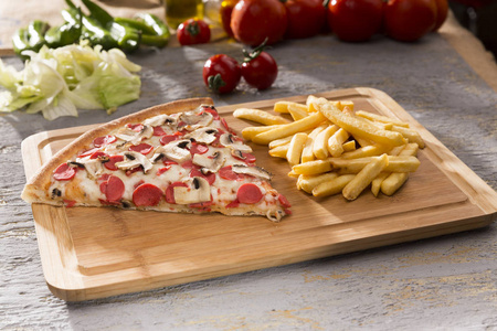 在木切割板上近距离观看意大利披萨和炸薯条