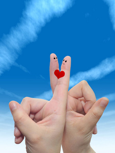 概念或概念人类或女性的双手，两个手指涂着红色的心，微笑的脸在云蓝色的天空背景上