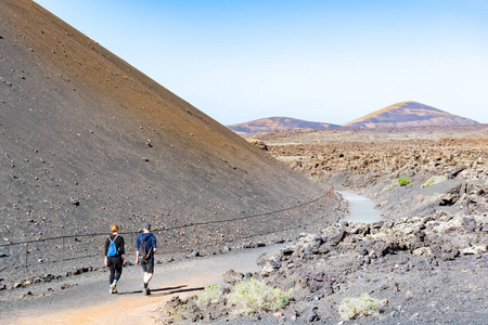 在西班牙加那利群岛兰萨罗特省 timanfaya 国家公园的 caldera de los cuervos 散步的游客