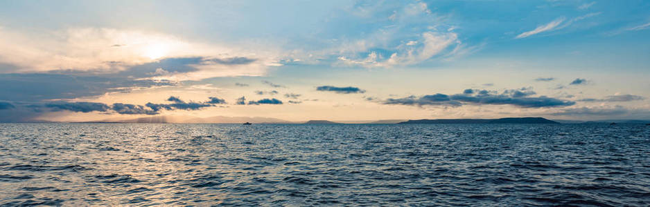美丽的日落在海上，倒影在水中，雄伟的云彩在天空中。 横幅长格式。