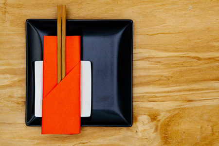 黑色陶瓷碗和竹筷子，用于用橙色餐巾纸做寿司的食物。