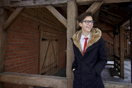 一个穿着毛领外套的年轻人的肖像。 以复古风格的木制建筑为背景。