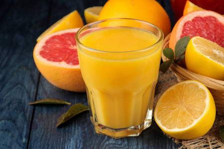 柑橘汁。 在蓝色的木桌上放着新鲜水果的橙汁。 近点