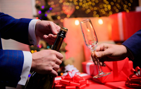 喝香槟或起泡酒。用香槟庆祝新年。新年前的最后一分钟。新年倒计时。手打开香槟酒瓶, 并举行玻璃圣诞装饰背景