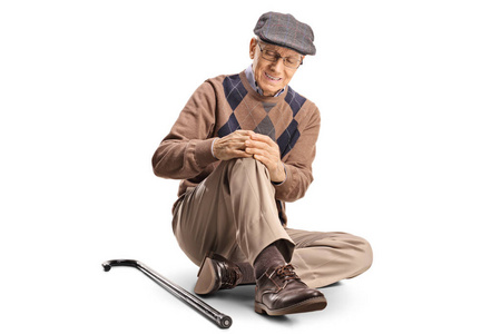 老人坐在地板上,抱着他痛苦的膝盖照片