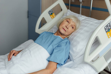 伤心的老年妇女躺在医院的床上，望着远方
