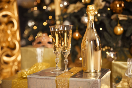 带两杯的金色香槟瓶。 圣诞节庆祝概念。