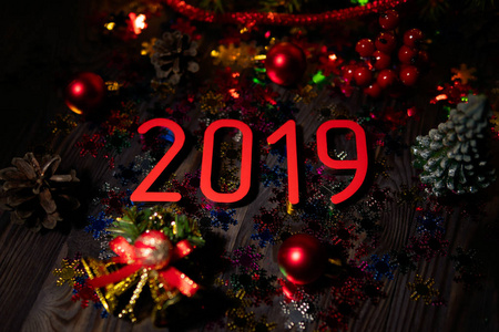 由上面组成的鲜红数字2019年新年在木制桌子上，有闪光和装饰品