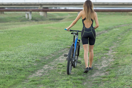 女孩骑着山地车在越野上,美丽的肖像自行车在日落健身女孩骑着现代碳