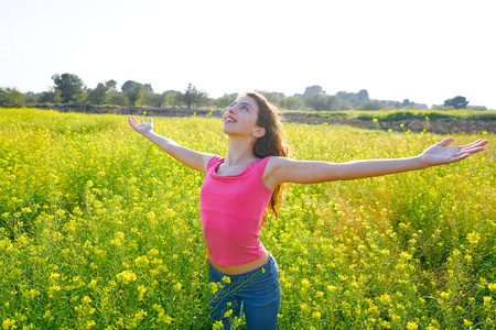 张开双臂快乐的春草地棕发少女照片