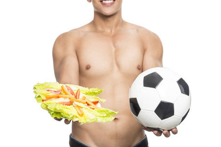 年轻健康的男人，手里拿着足球和一个苹果