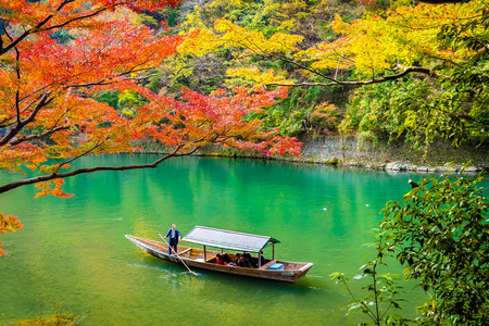 秋季日本京都，美丽的山河，有枫叶树和船绕湖而行