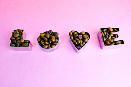 美丽的纹理与字爱情人节题字由烤选定的棕色天然芳香阿拉比卡咖啡豆, 罗布斯塔复制空间, 平坦的铺设, 粉红色的紫色背景