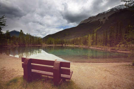 加拿大山湖旁的宁静景象，倒影着平静的水中的岩石。