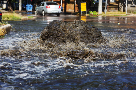 事故污水处理系统。 水从下水道流过道路。 下水道里的事故。 突破污水系统。 水从沙井里流出。 在道路上的污水井上浇制供水系统