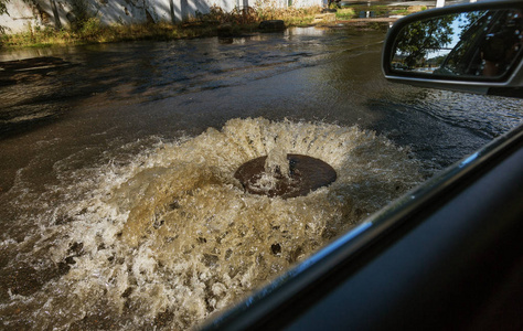 水从道路污水舱口流出。 污水的排水喷泉。 污水系统事故。 肮脏的污水在道路上流动喷泉。 从舱口流出的水