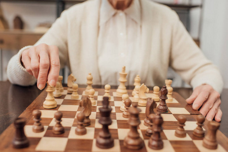 老年妇女坐在餐桌旁，在家下棋