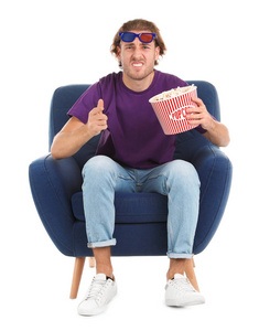 在白色背景电影放映期间，情绪激动的男人，带着3D眼镜和爆米花坐在扶手椅上