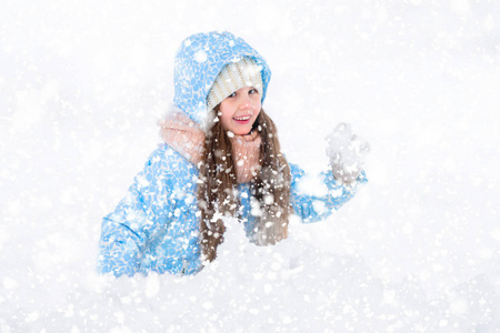 快乐的女孩玩冬季户外游戏，瞄准雪球打雪仗对着镜头。