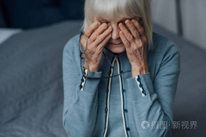 戴着眼镜白发擦着眼泪在家哭泣的老女人心烦意乱