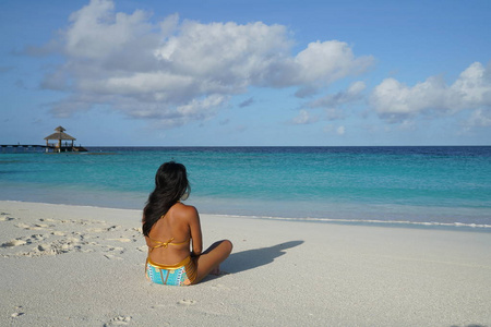 穿比基尼的女人坐在阳光下的沙滩上