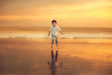 在令人惊叹的日落时分，欢快的男孩在海滩上奔跑