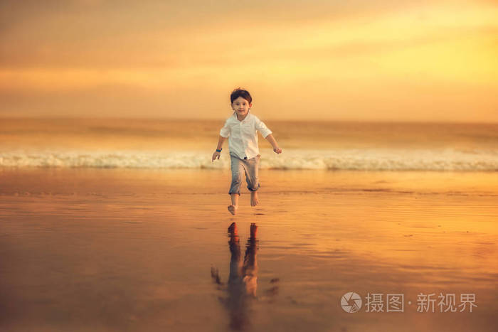 在令人惊叹的日落时分,欢快的男孩在海滩上奔跑