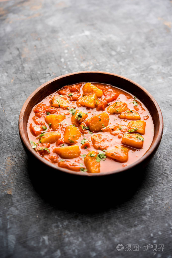 用香料和香草在番茄咖喱中煮熟的土豆.在碗里端上穆迪背景.选择性聚焦