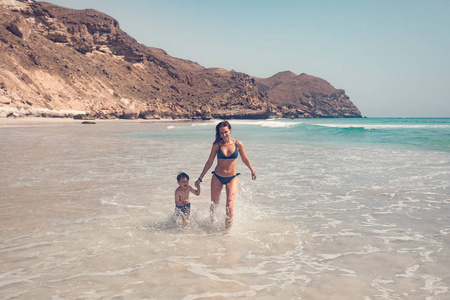 在阳光明媚的日子里，母亲和儿子在海滩上奔跑